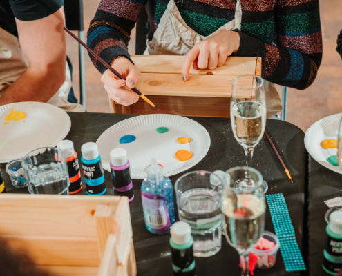 Vrolijke deelnemers aan de workshop 'Pimp mijn doos' bij Paaldansstudio & Dance Centre genieten van creatieve verfraaiingen en artistieke expressie.